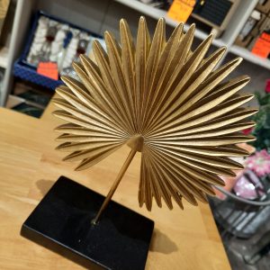 a gold metal fan shaped ornament on a black stand