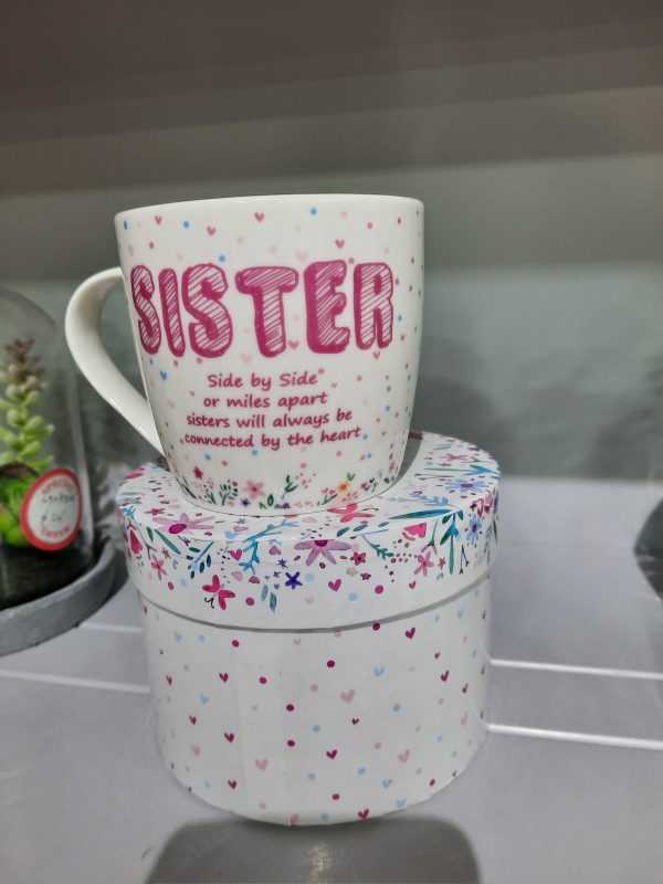 a white mug with sister written in pink
