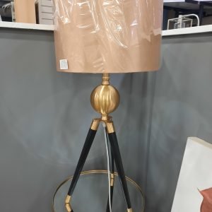 black metal lamp with tripod legs and gold detail with a gold shade