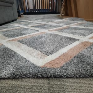 an image of a grey rug with designs in cream and beige on a floor