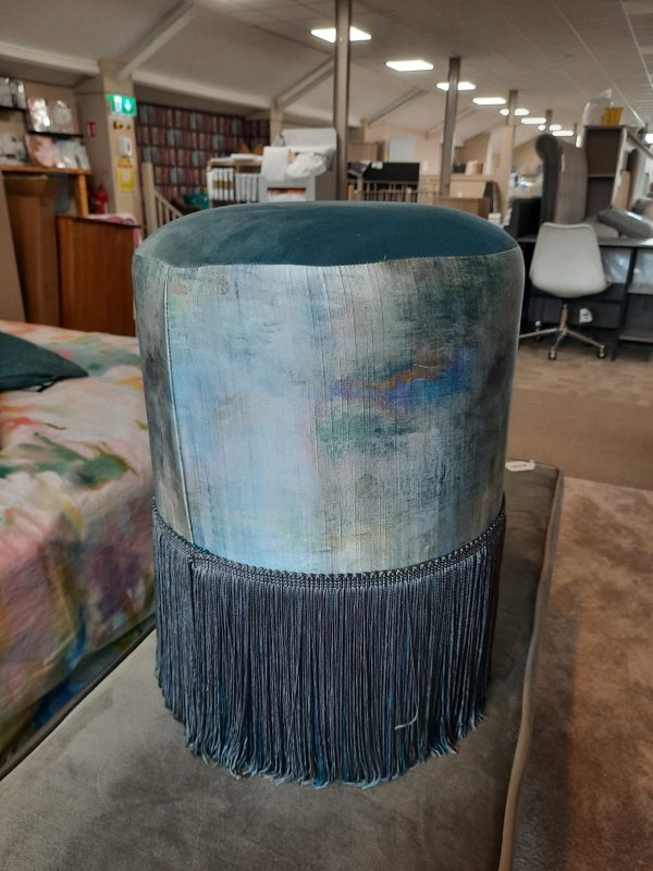 an image of a fringed footstool in teal